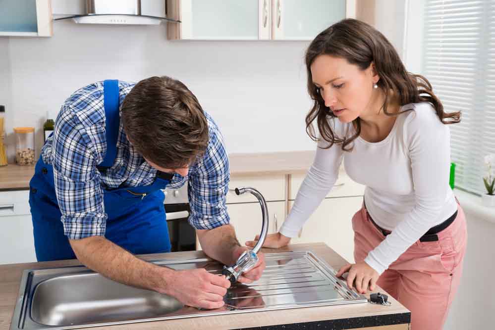Chapman Plumbing technician helping a customer at a kitchen sink